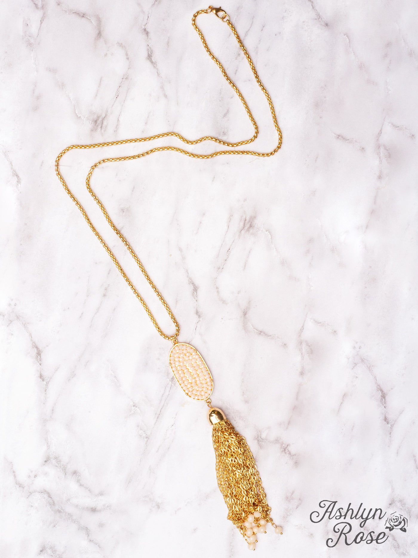 A LITTLE SPARKLE WHITE CRYSTAL OVAL PENDANT TASSEL ON A GOLD NECKLACE